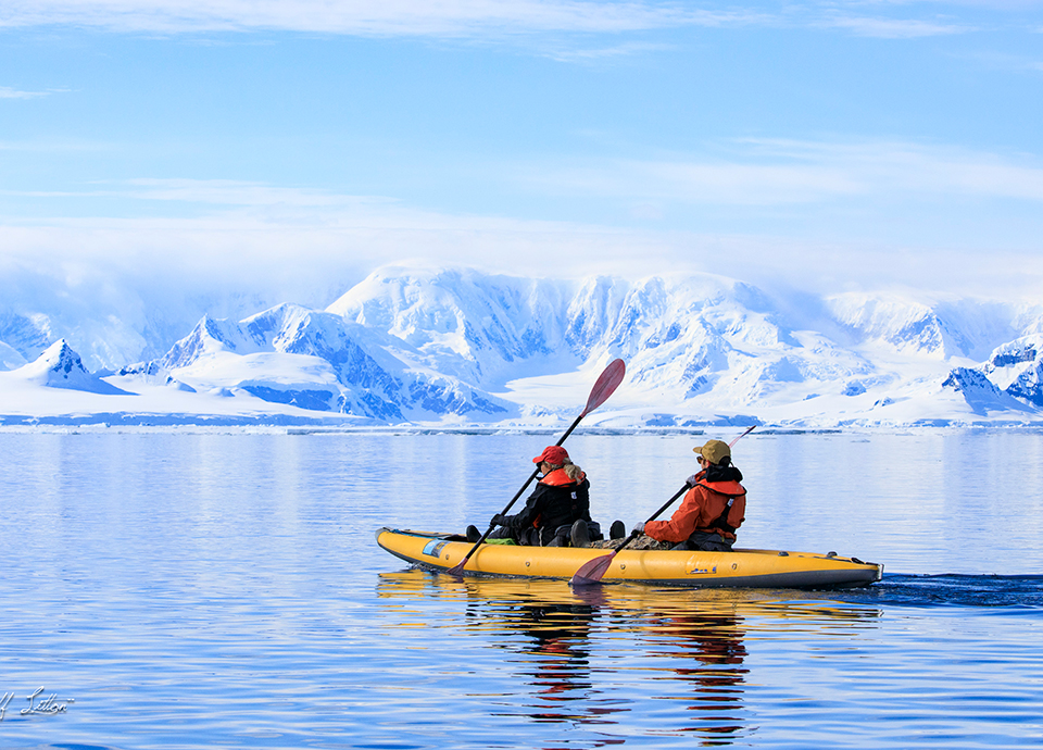 Paddling under a clear blue sky in the waters off the Antarctic Peninsula.