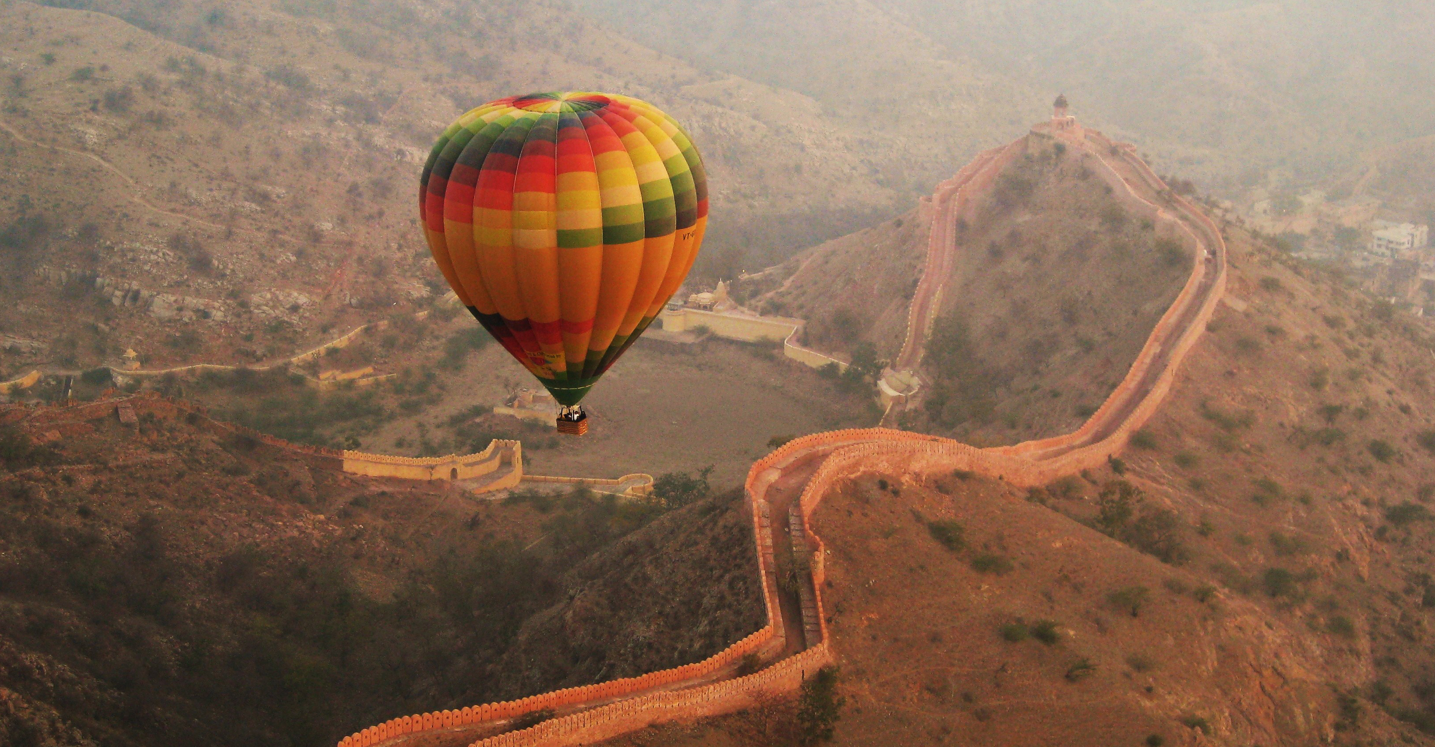 A hot air balloon floats over a sandstone fort in Jaipur, India