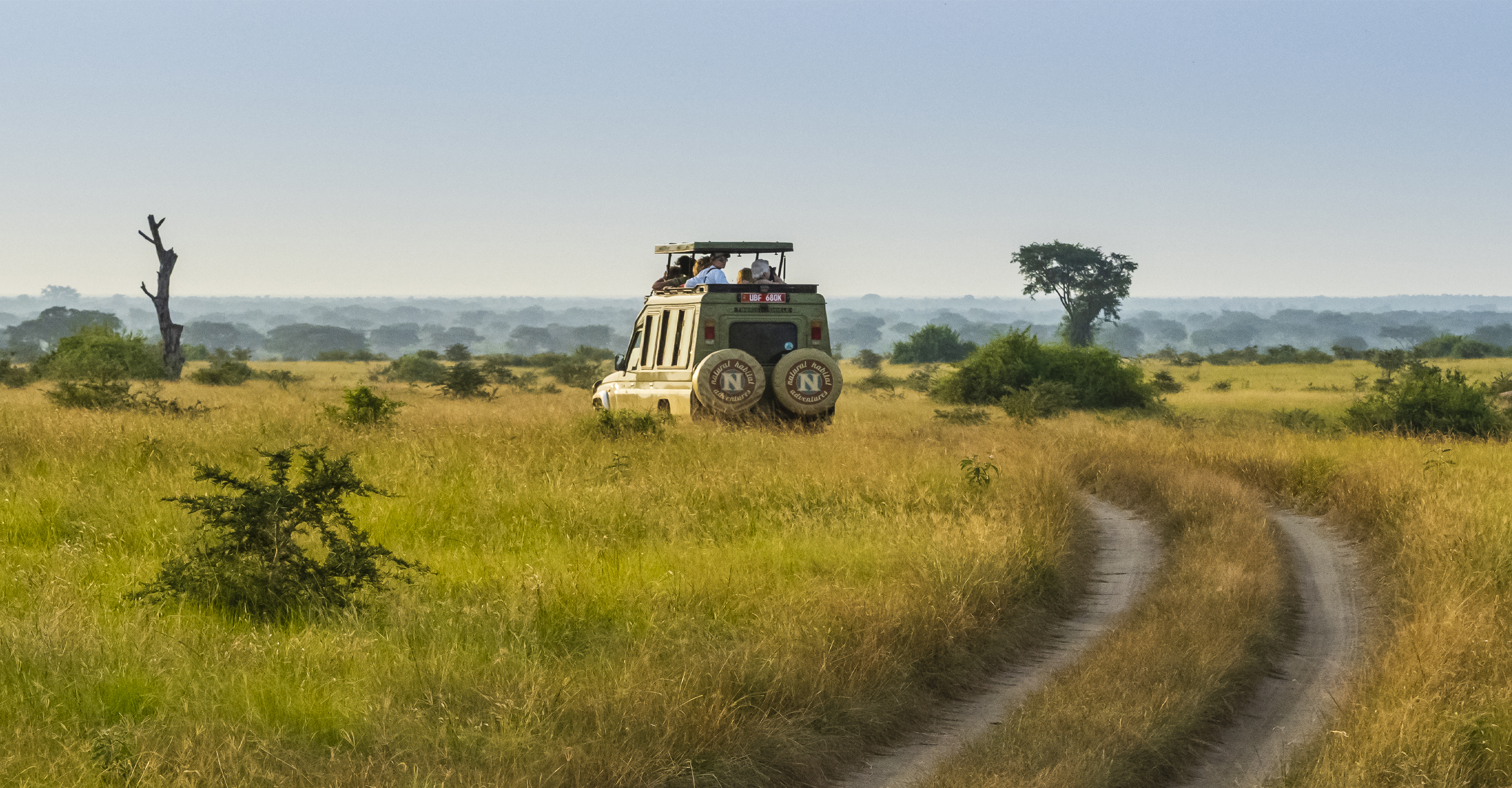 A Natural Habitat Safari vehicle stops on a road so travelers can view wildlife, Serengeti National Park, Tanzania