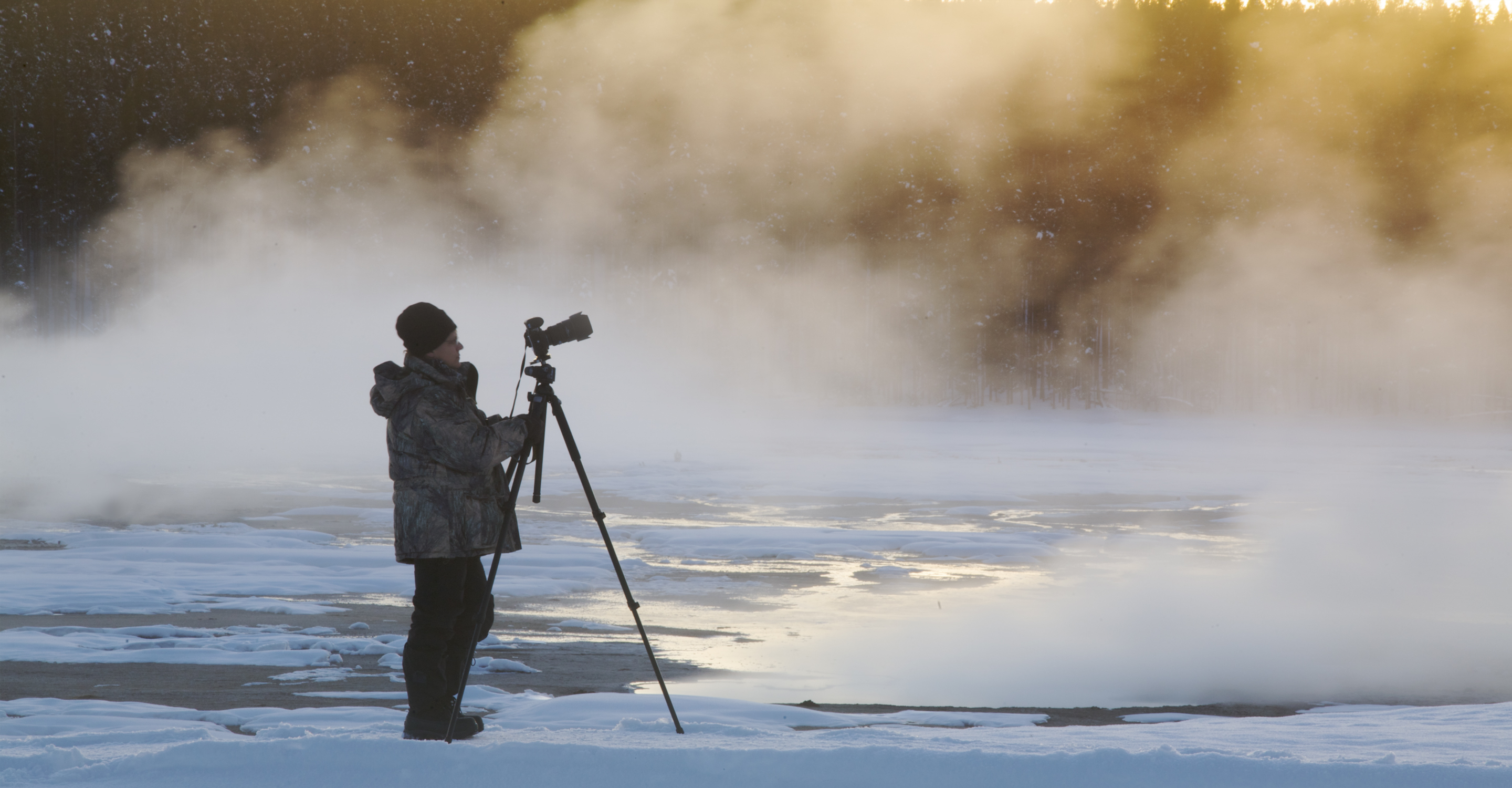A photographer stands near hot springs in Yellowstone National Park, United States