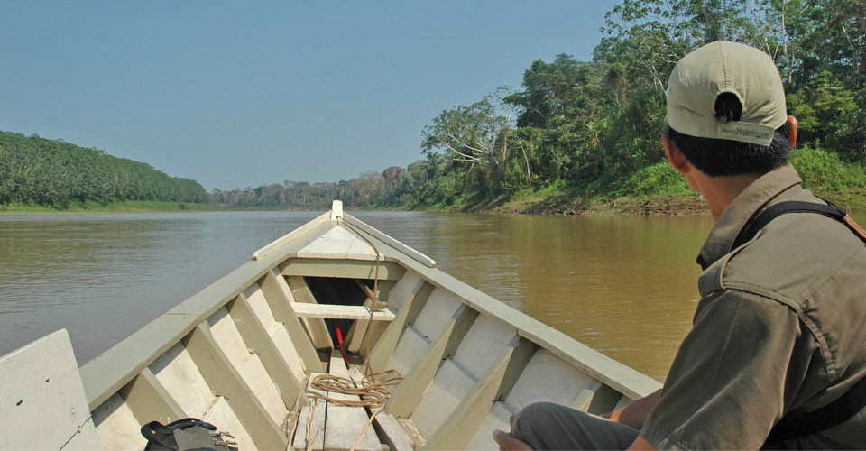 A guide sits in a boat traveling along the Amazon River, Pacaya-Samiria National Reserve, Peru