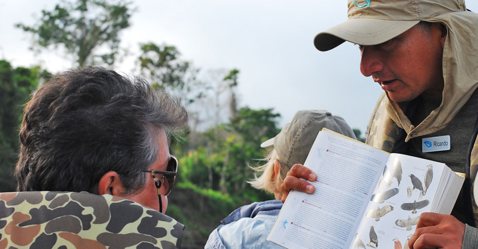 A guide shows a traveler a birding book, Pacaya-Samiria National Reserve, Peru