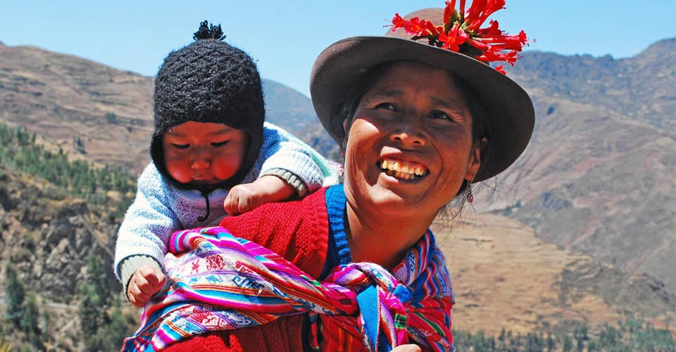 AN indigenous woman carries a baby on her back, Pisac, Sacred Valley, Peru