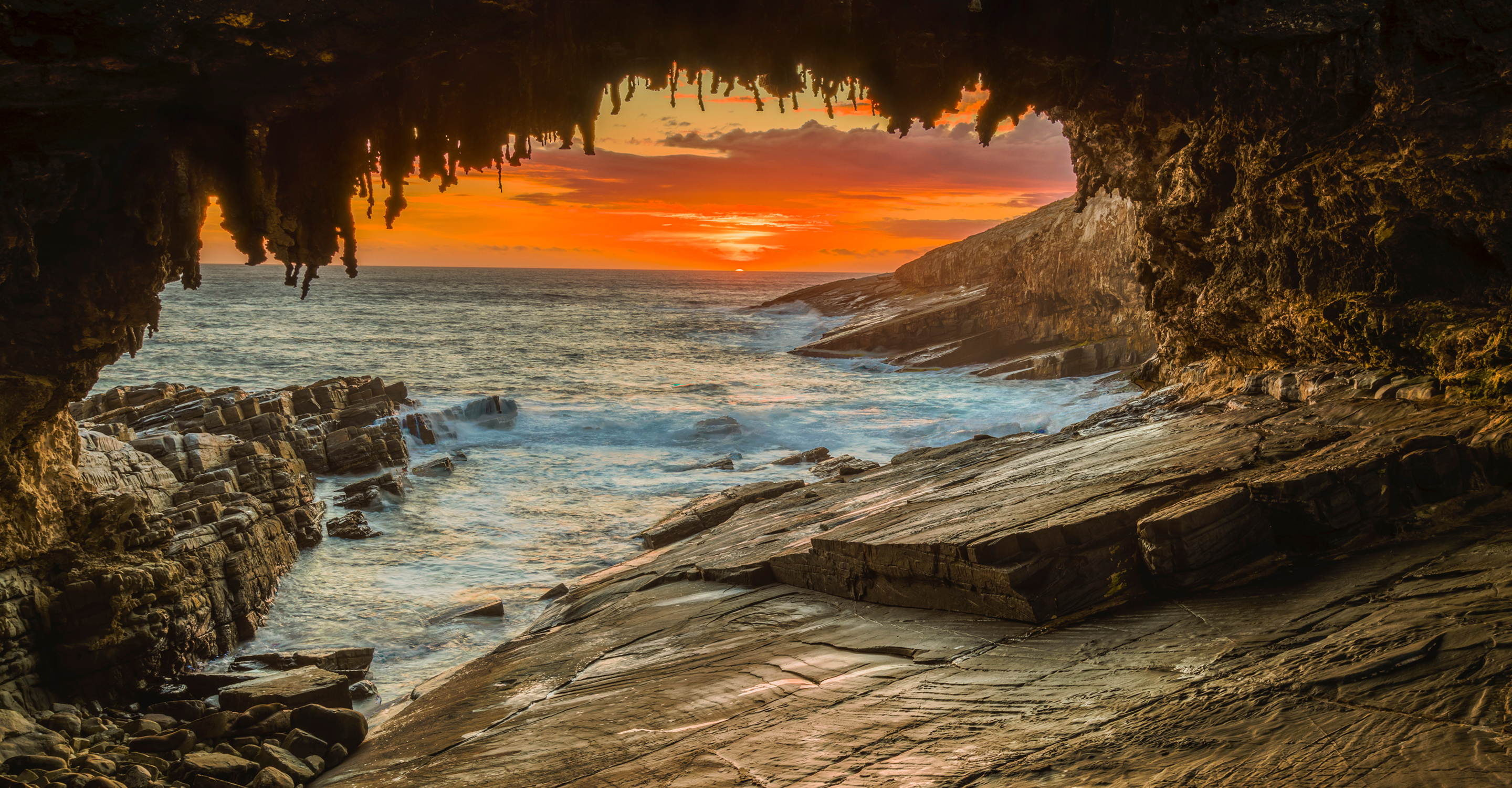 View of the ocean through Admirals Arch at sunset, Australia