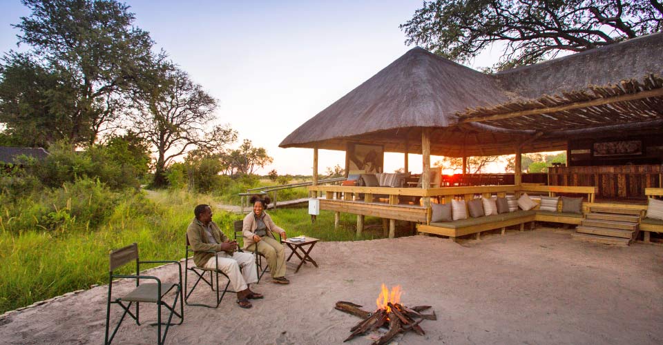 Two people relax by the fire at the Jackal & camp; Hide, Khwai Private Reserve, Botswana