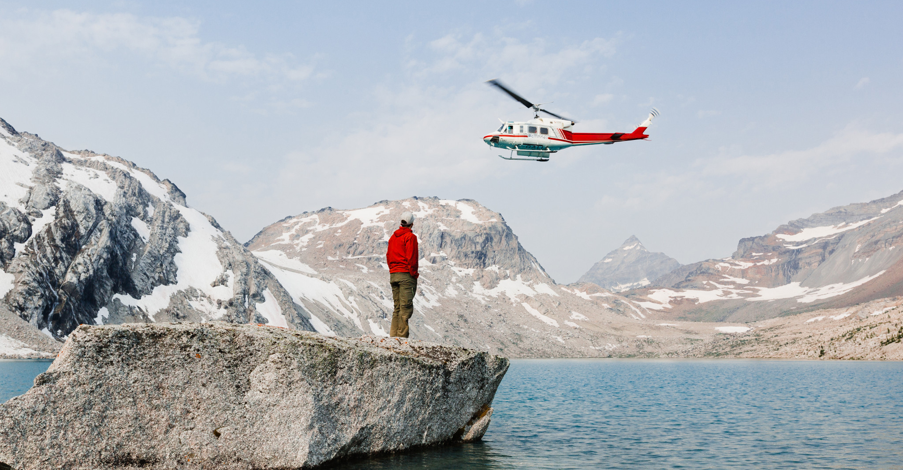 A traveler waits for a helicopter overhead, Yoho National Park, Alberta, Canada