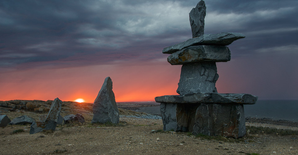 An inukshuk on the coastline of Churchill at sunset, Manitoba, Canada;