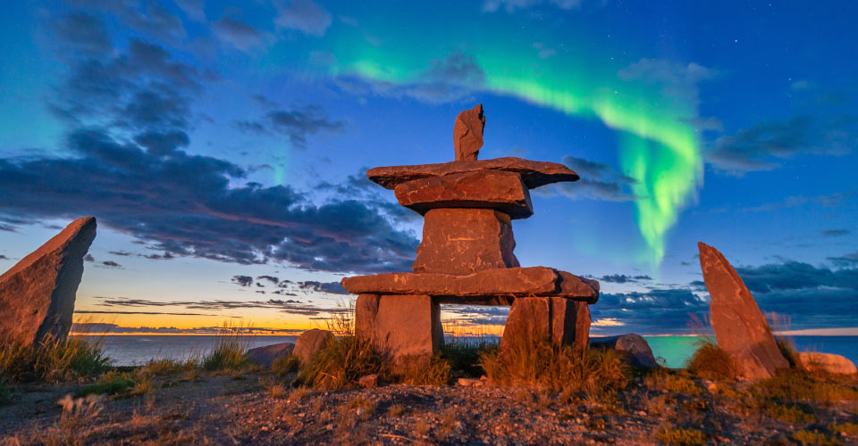 Northern lights above an inukshuk on the coastline in Churchill, Manitoba, Canada;