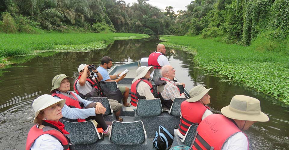 Travelers view wildlife from a boat during a river cruise in Tortuguero National Park, Costa Rica
