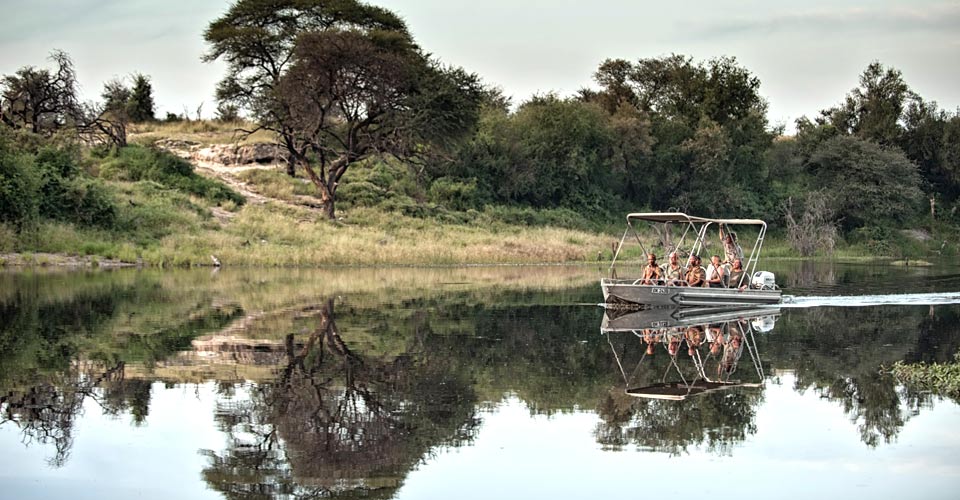 A group of travelers and their guides cruise in a boat in the Boteti River, Botswana