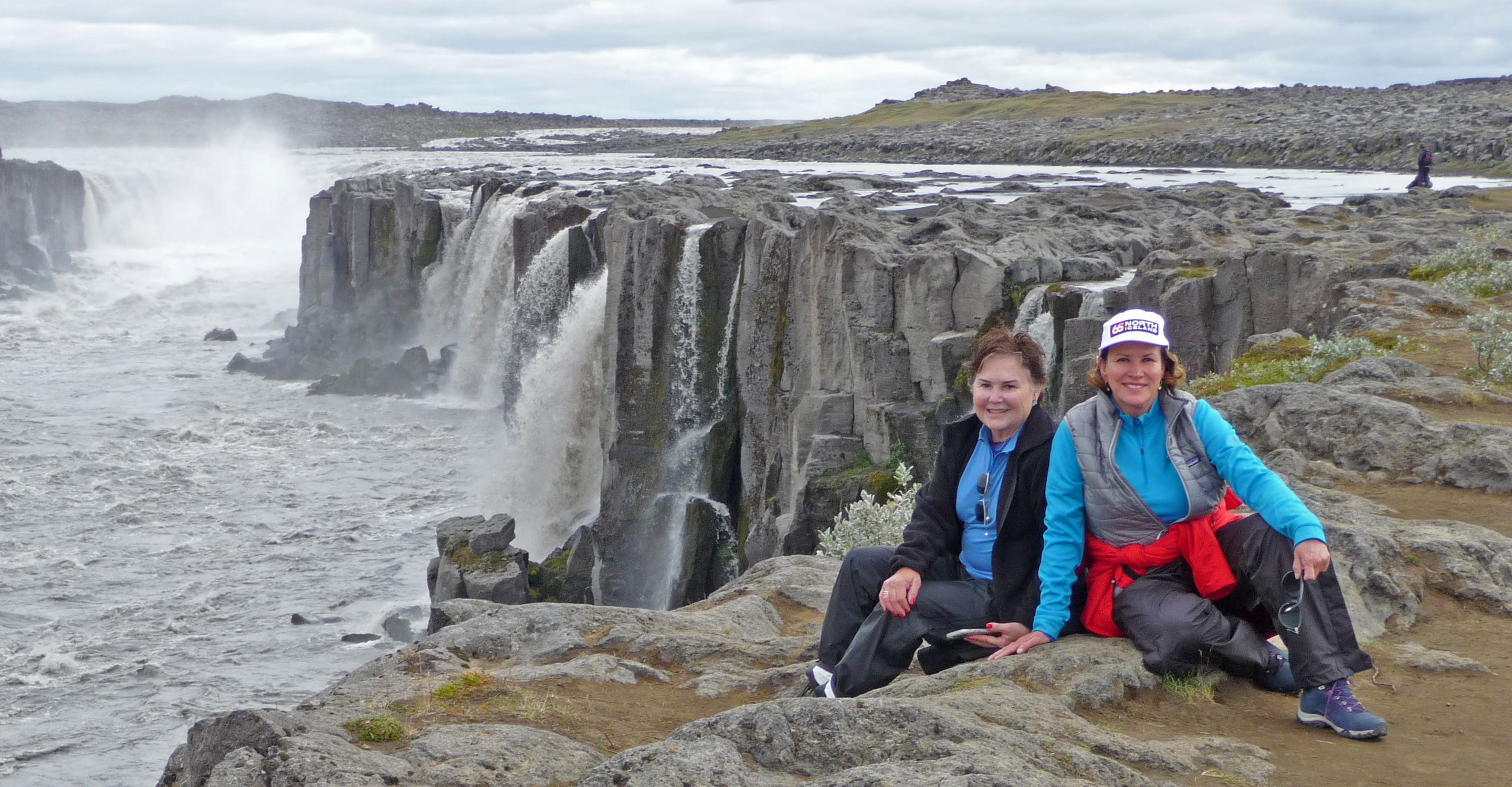 Travelers smile in front of Godafoss waterfall, Iceland, Europe