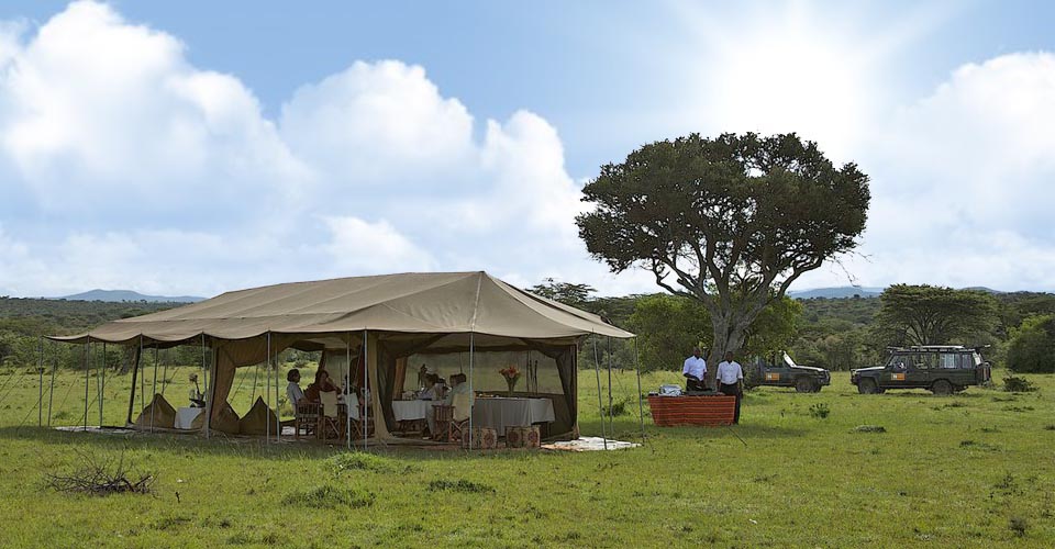 Travelers enjoy a meal at Natural Habitat's Migration Base Camp, Maasai Mara National Reserve, Kenya