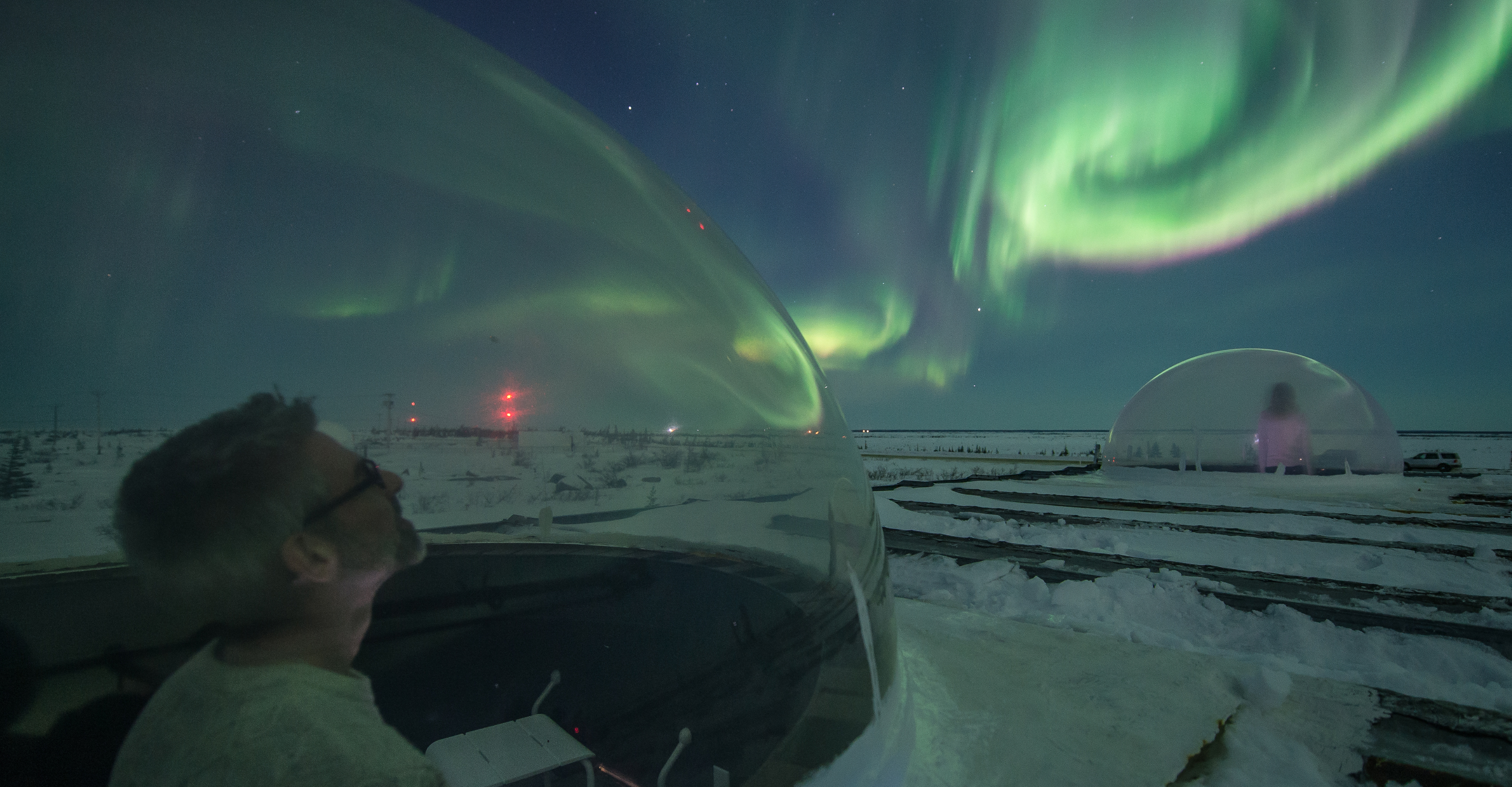 Travelers view the northern lights from Aurora Domes in Churchill, Manitoba, Canada