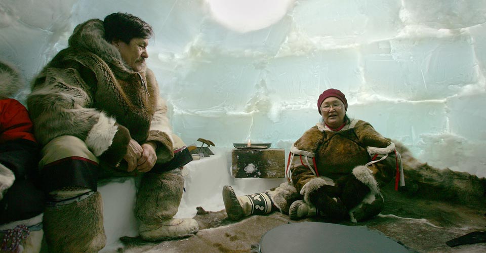 Two indigenous people sit inside an igloo, Churchill, Manitoba, Canada;