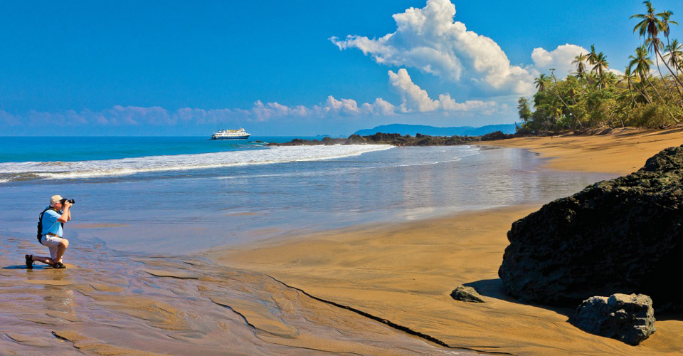 A traveler takes photos on the beach, Corcovado National Park, Costa Rica