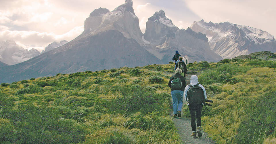 Travelers hike in Torres del Paine National Park with the granite towers in the background, Patagonia, Chile