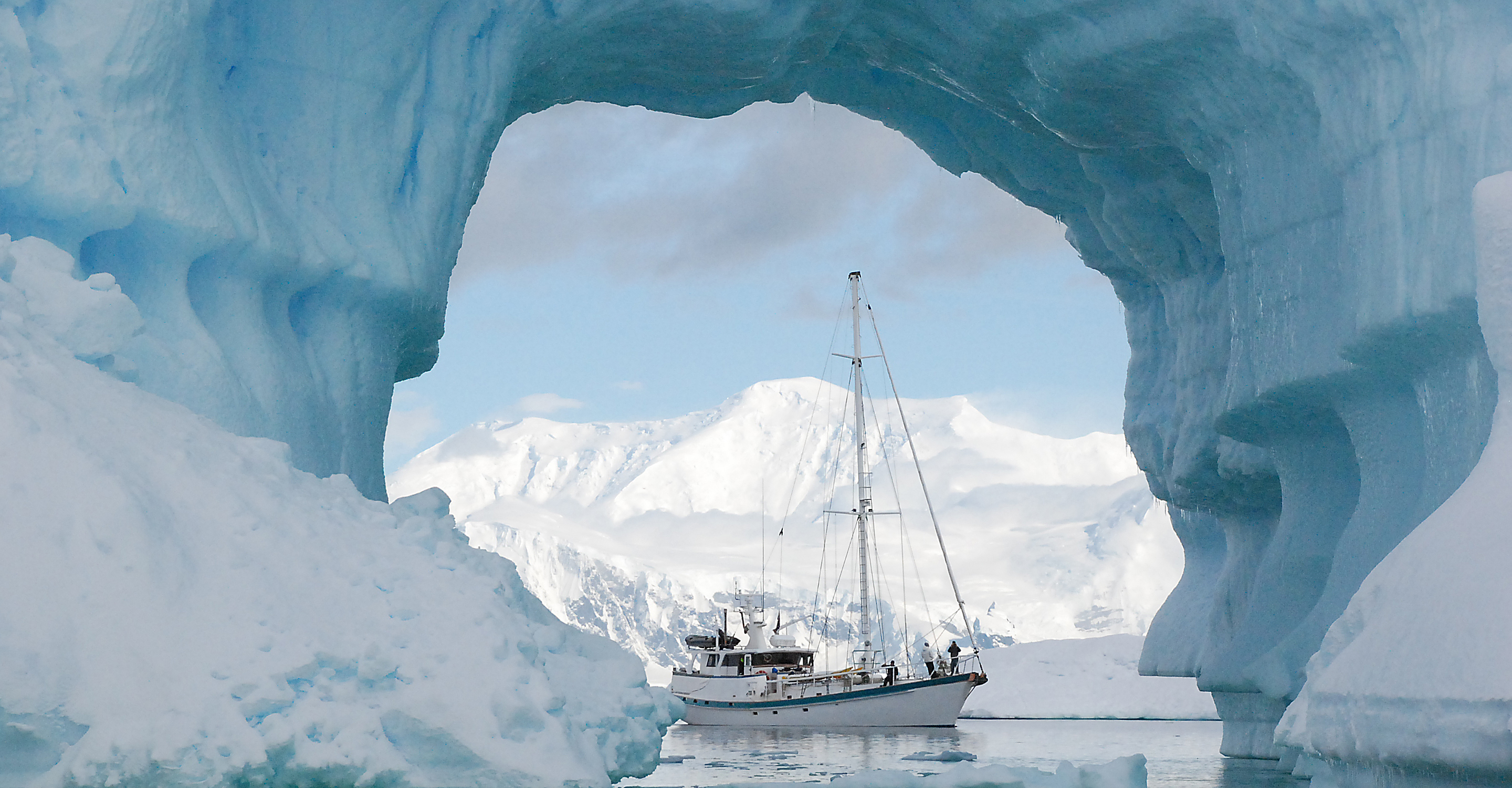 A view of the S/V Australis through an arched iceberg, Antarctica