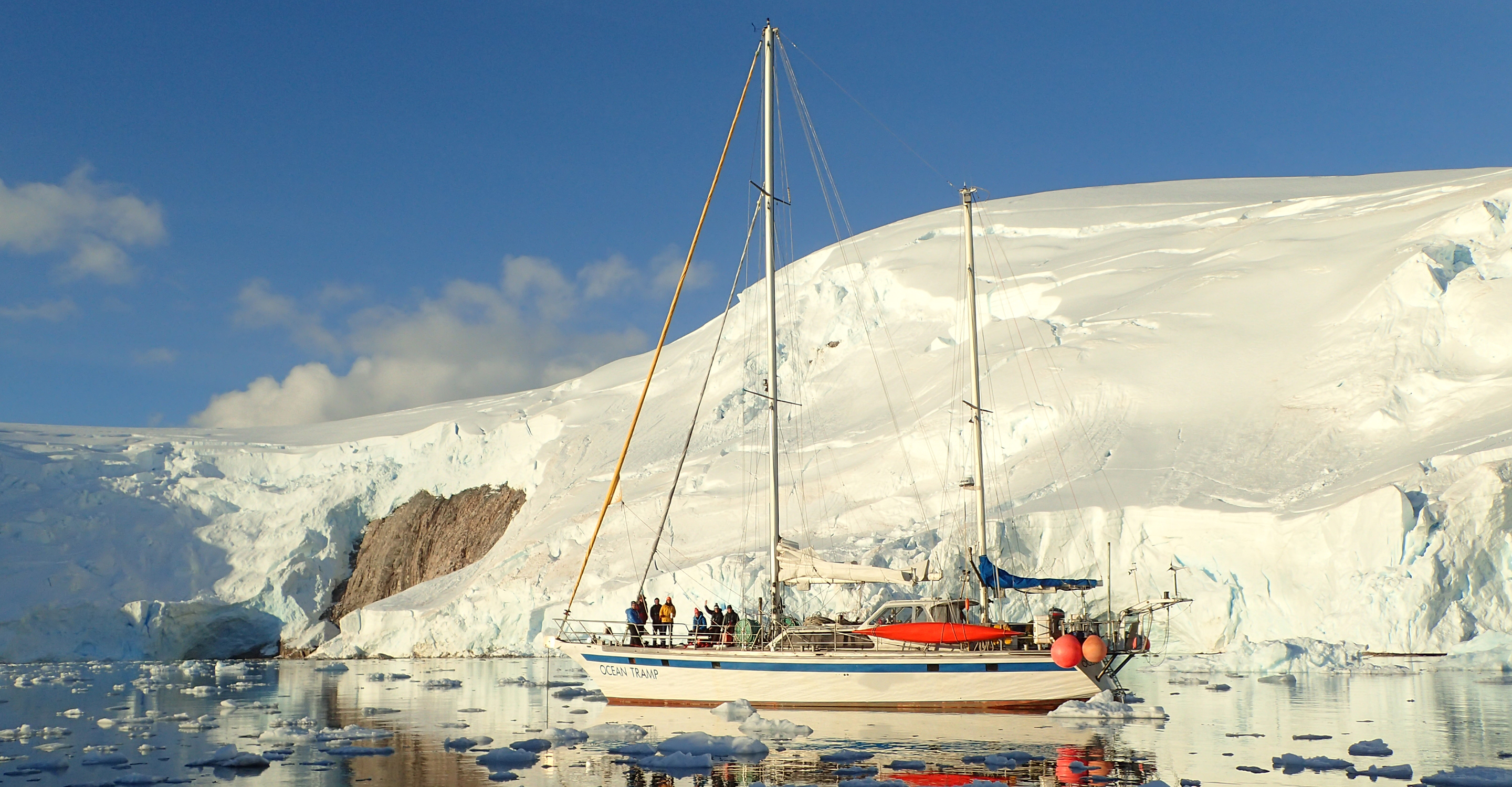 Travelers wave from the bow of the Ocean Tramp in the waters off of Antarctica