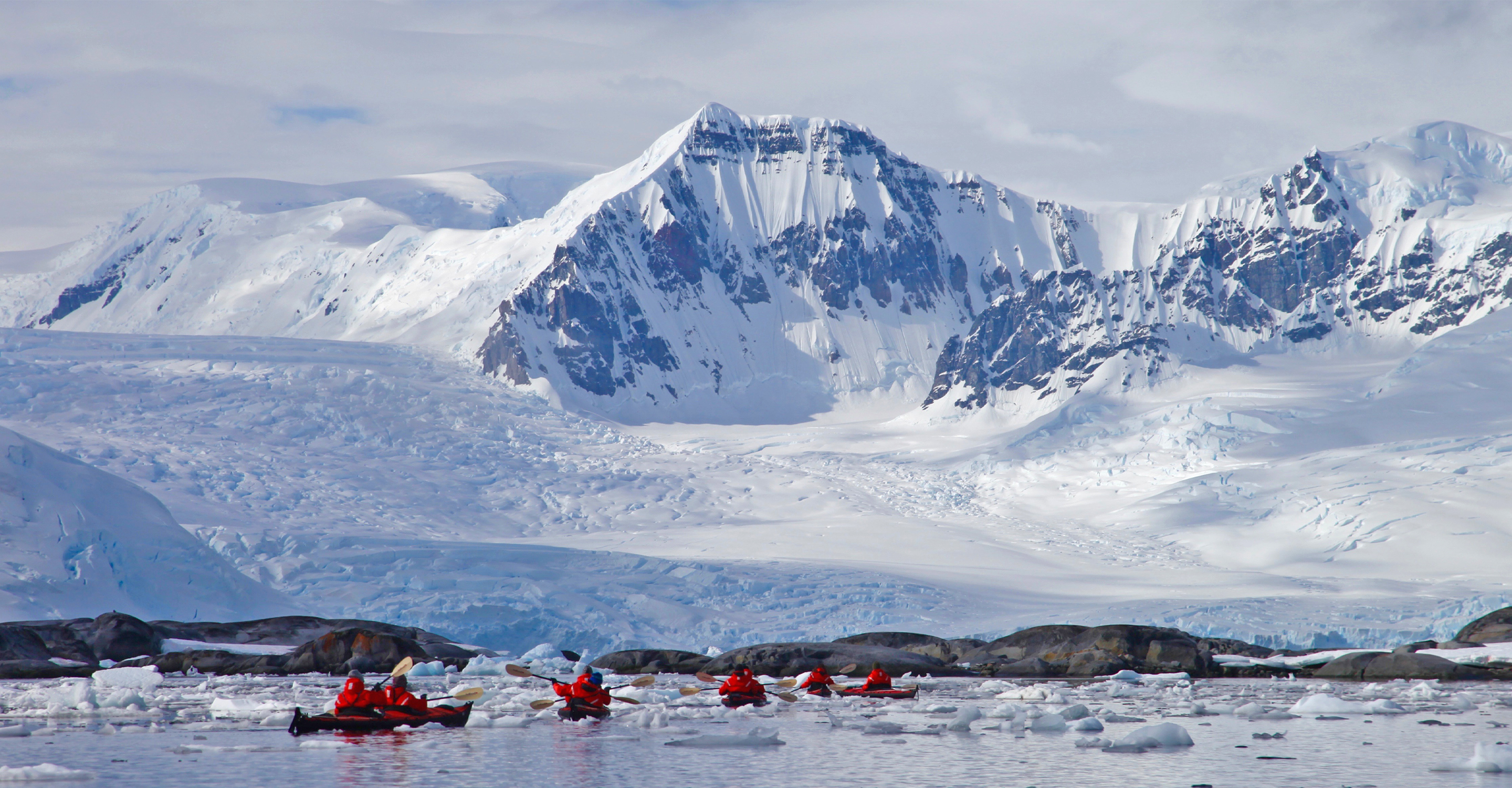 Natural Habitat Adventures travelers kayak through the icy waters in Antarctica