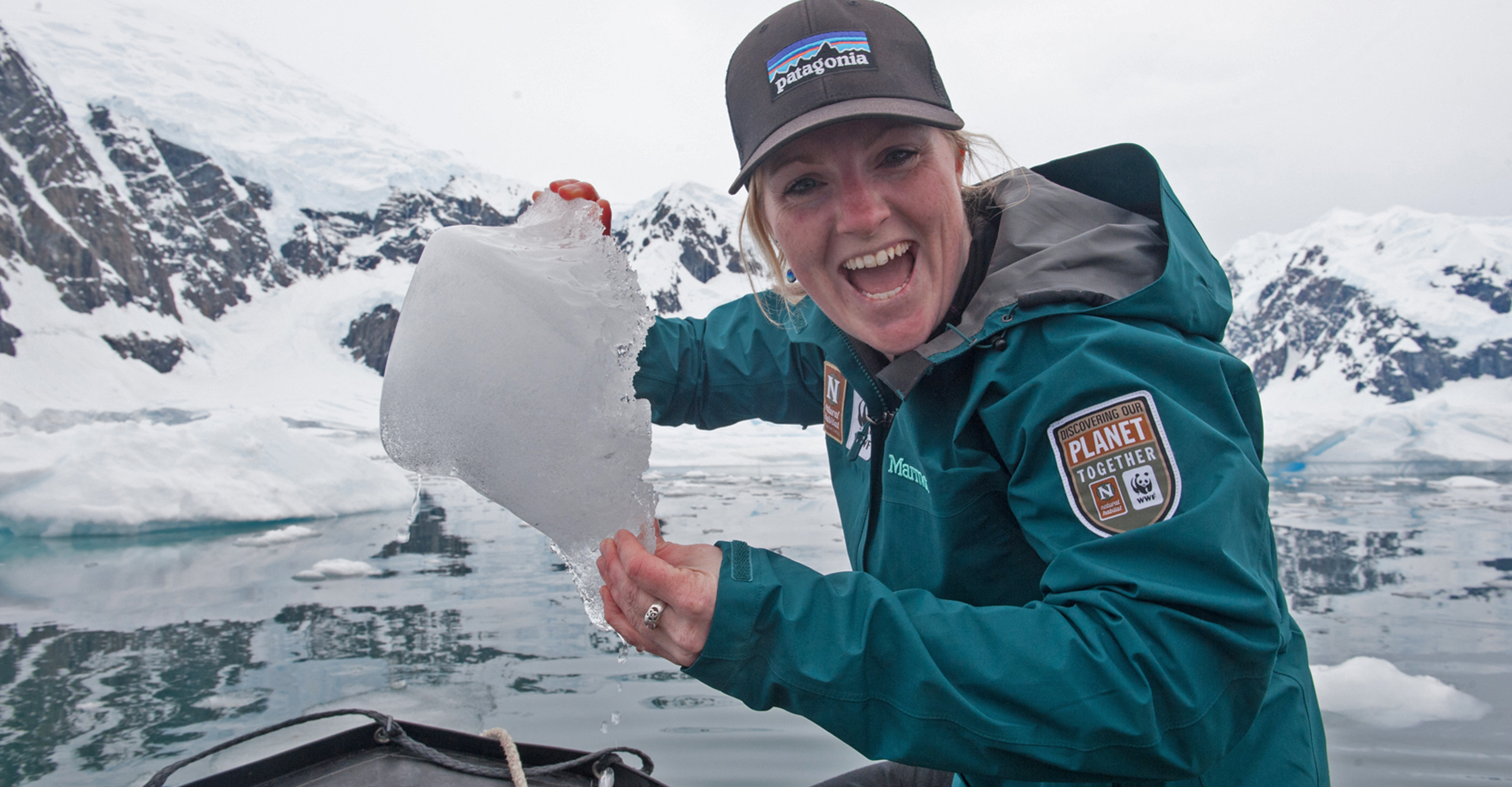A Natural Habitat Adventures Expedition Leader smiles with a chunk of ice from the waters off Antarctica