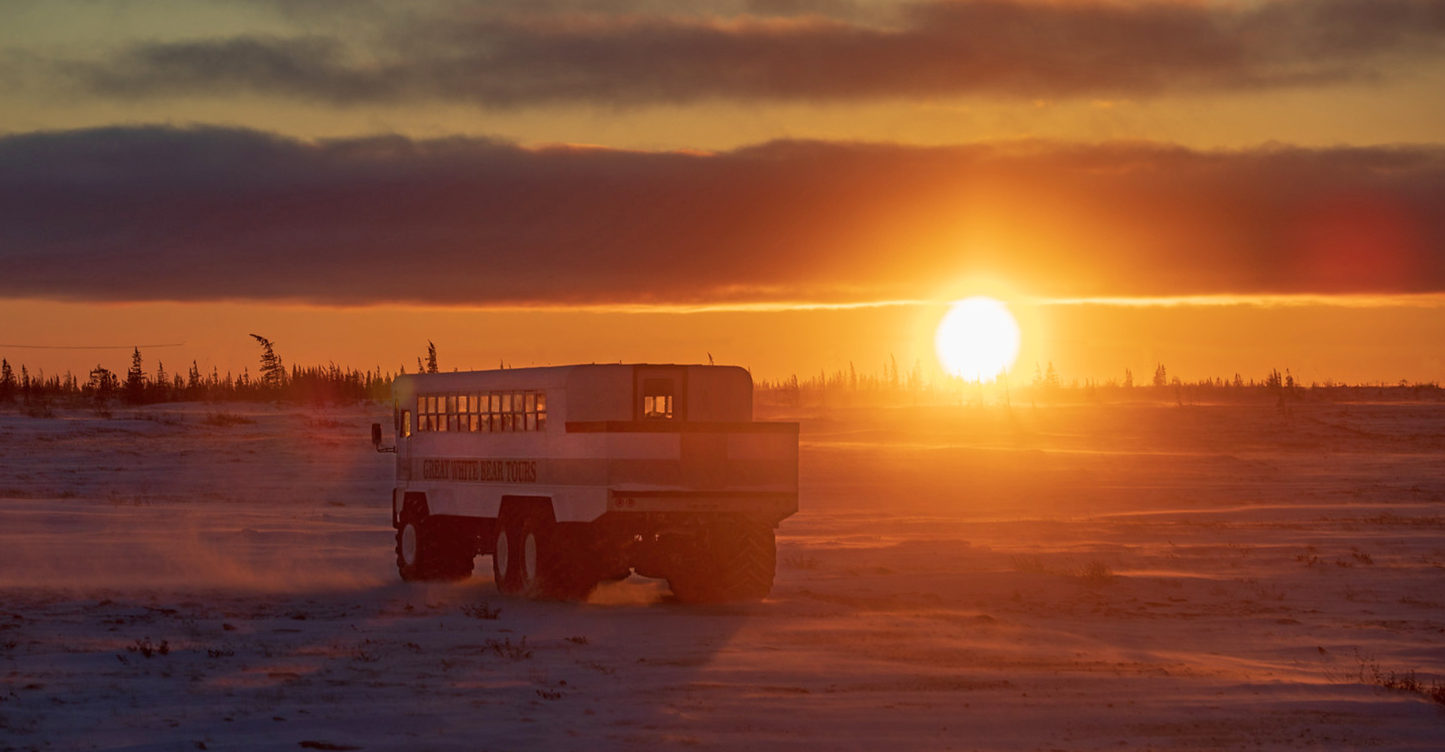 A Polar Rover drives through the tundra at sunset, Hudson Bay, Churchill, Manitoba, Canada