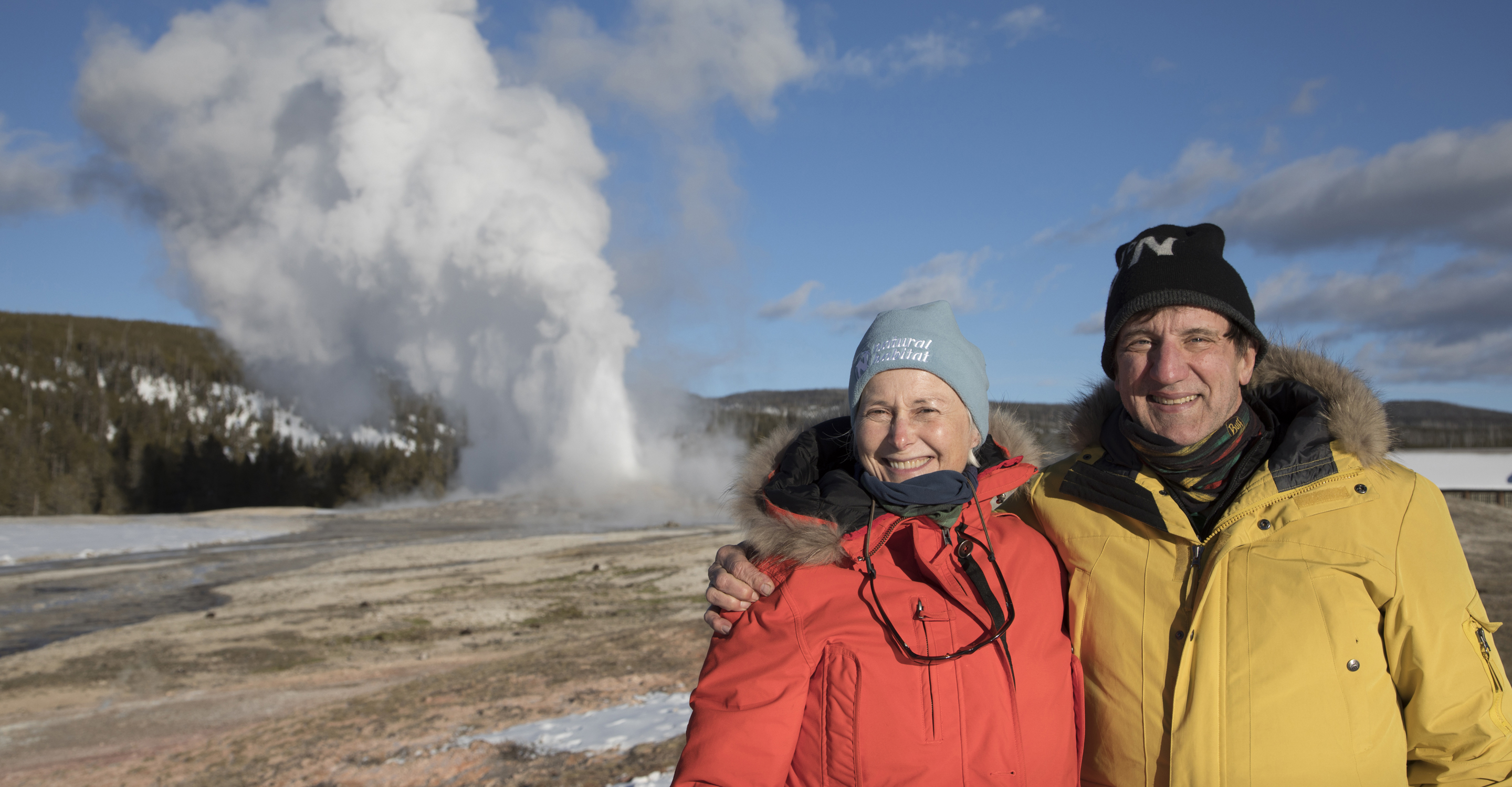 Happy travelers standing in front of a geyser in Yellowstone National Park, United States