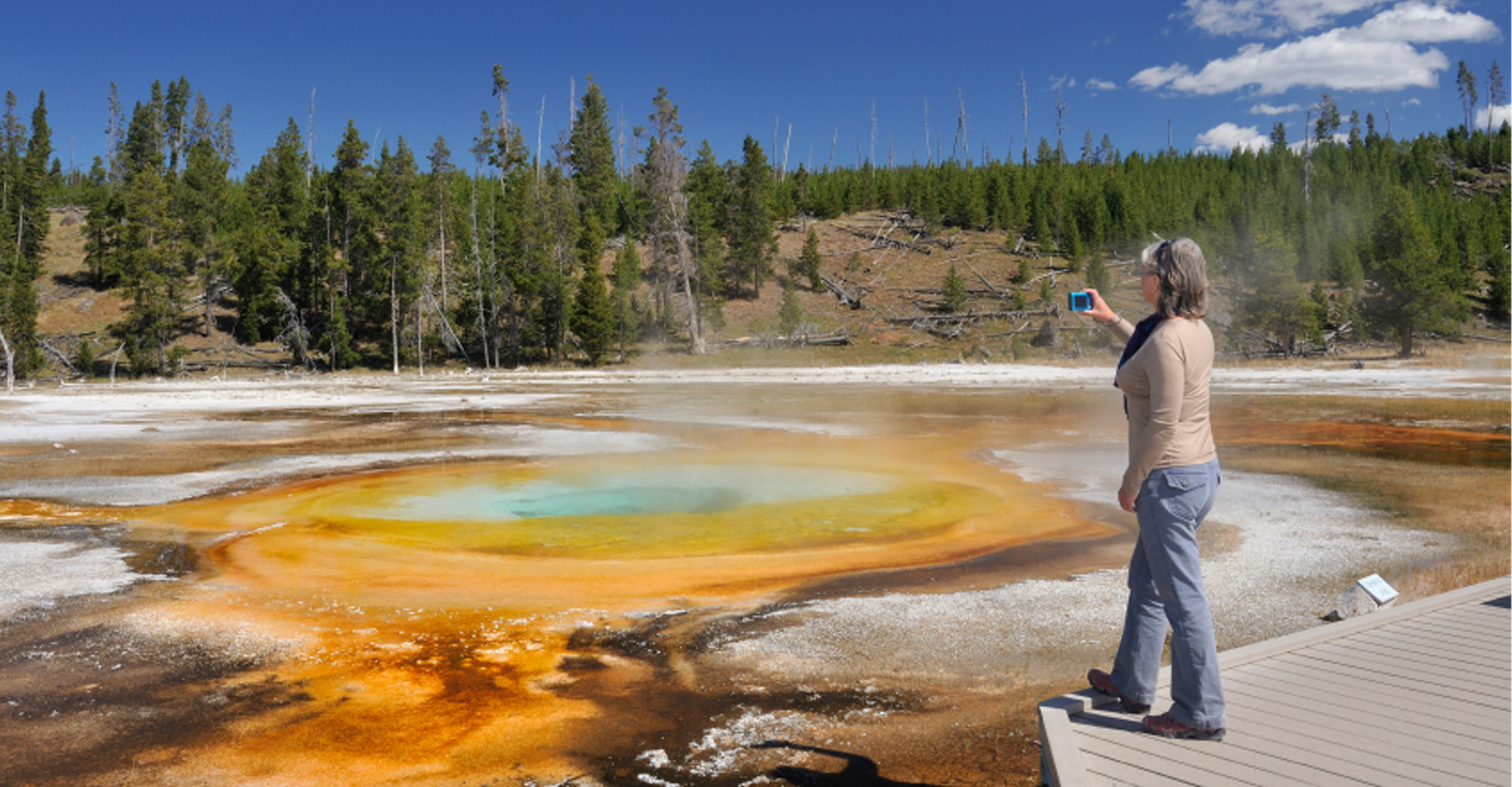 Traveler photographs a hot spring in Yellowstone National Park, United States