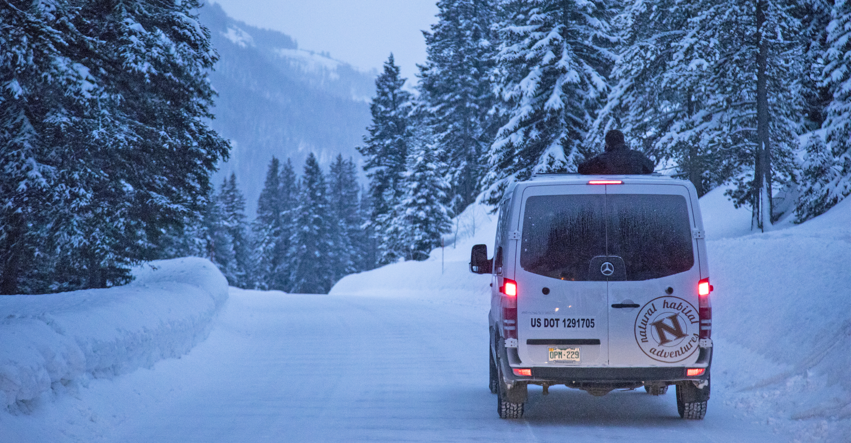 A Natural Habitat Adventures Sprinter parks along a snowy road in Yellowstone National Park, United States